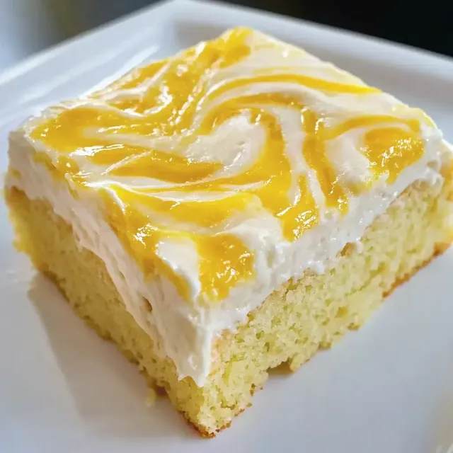 Ein Stück Kuchen mit einer cremigen, gelb-weißen Glasur auf einer weißen Platte.