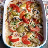 Ein Auflauf mit einer cremigen Soße, belegt mit roten und grünen Paprika, Pilzen und frischem Kräutern.