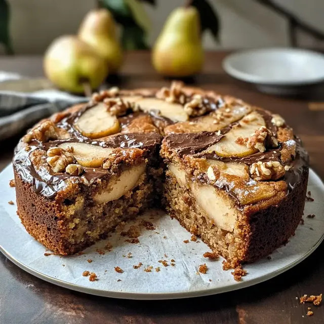Ein auf einem Teller angerichteter Kuchen mit Äpfeln, Schokoladenglasur und Walnüssen, von dem ein Stück herausgeschnitten wurde.