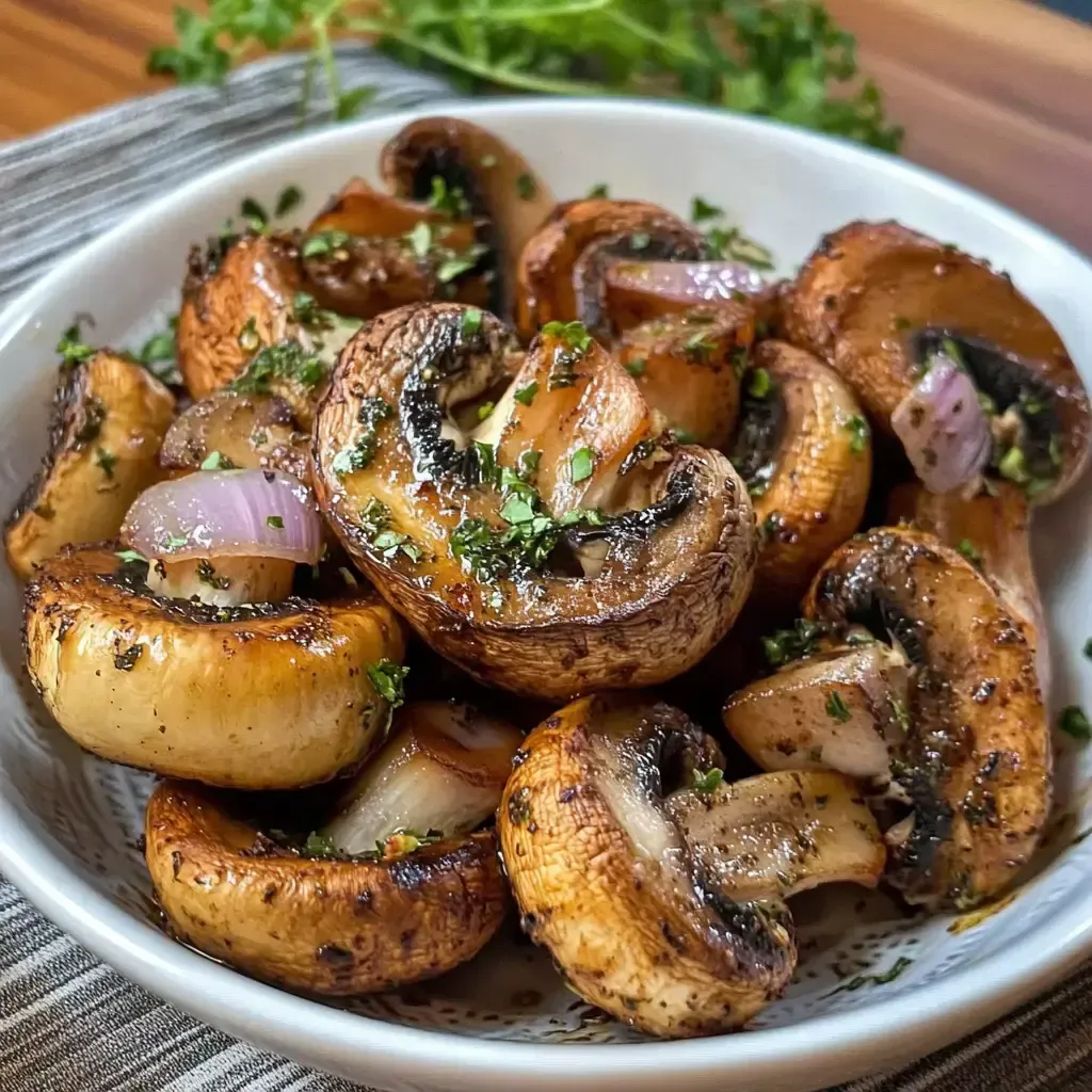 Ein Teller mit gebratenen Champignons und Zwiebeln, garniert mit frischen Kräutern.