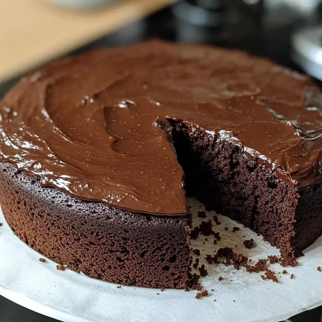 Ein saftiger Schokoladenkuchen mit glatter Glasur, aus dem ein Stück herausgeschnitten wurde.