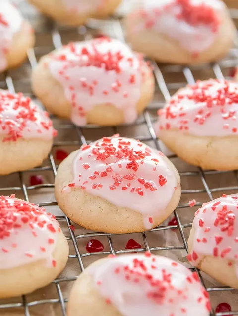 A tray of almond cherry cookies with red and white sprinkles.