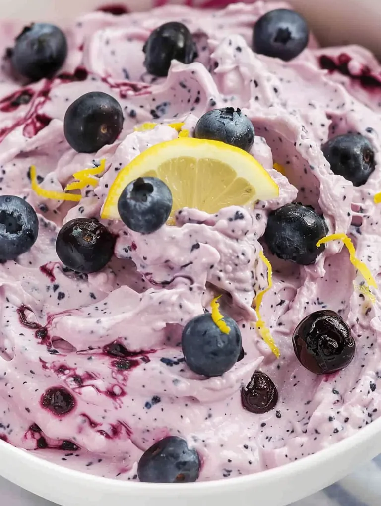 A bowl of blueberry fluff with a lemon wedge on top.